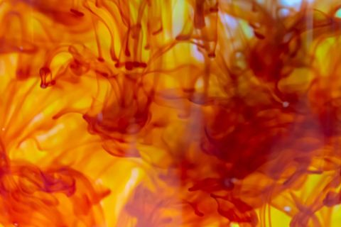 Fiery ink flowing in liquid with vibrant red and yellow swirls for abstract background