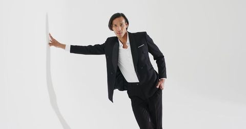 Asian man in elegant suit leaning against white wall