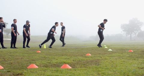 Athletes Training in Morning Fog with Cones on Field