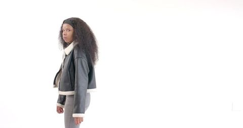 Confident woman in stylish leather jacket against white background