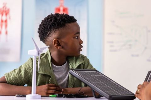 African american student testing solar panel and wind turbine during hands-on stem lesson