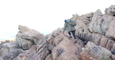Woman Climbing Rocky Terrain with Backpack and Mat