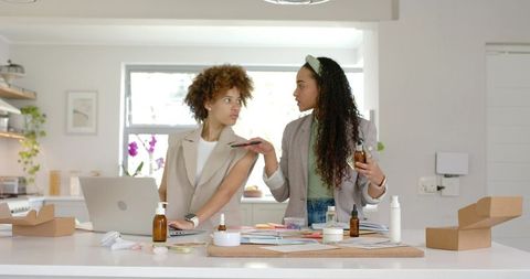 African american entrepreneurs testing amber cosmetic bottles at modern kitchen island