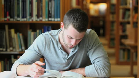 Focused Student Reading Book in Quiet Library Environment