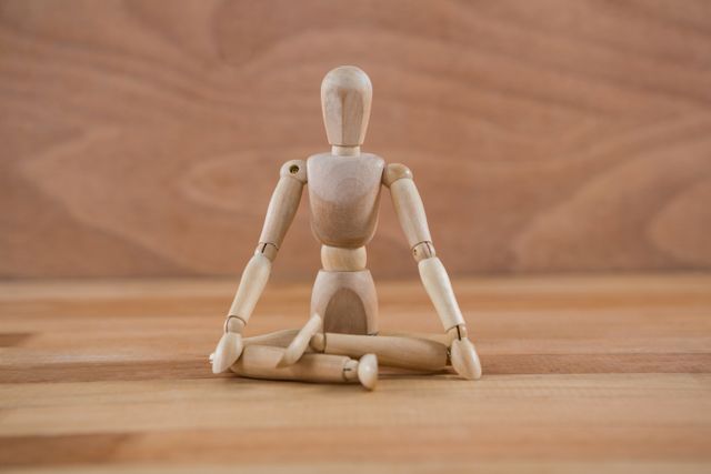 Wooden figurine sitting in a lotus position on wooden floor