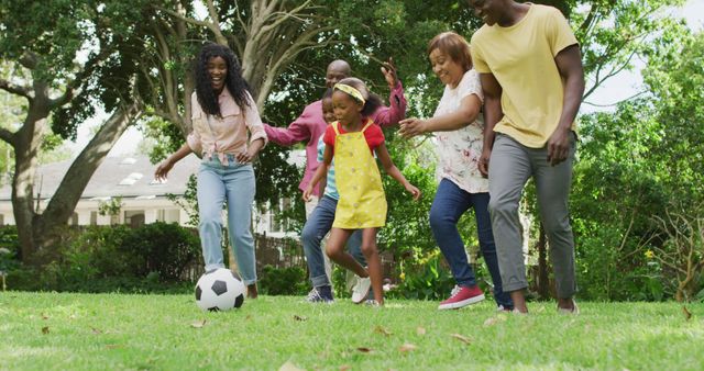 Image of happy african american family playing football in garden. family, togetherness, spending quality time together outdoors.