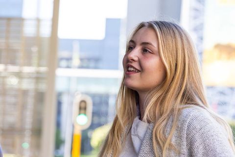Smiling young woman looking up and talking in urban plaza with green traffic light