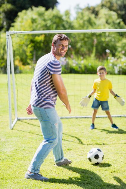 Father and son playing football in the park on a sunny day