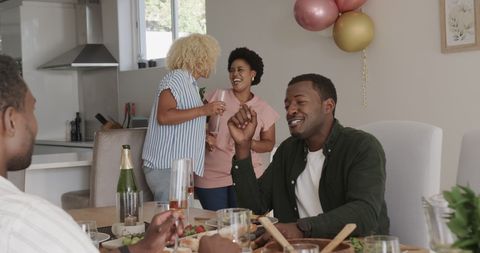 African American Friends Celebrating at Home with Drinks and Laughter