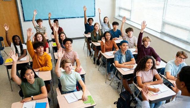 High school students raising hands in bright classroom participating in lesson and discussion