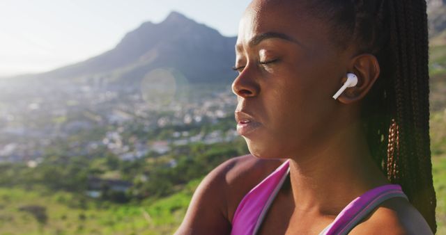 African american woman wearing wireless earphones stretching her arms outdoors. fitness sports and active lifestyle concept