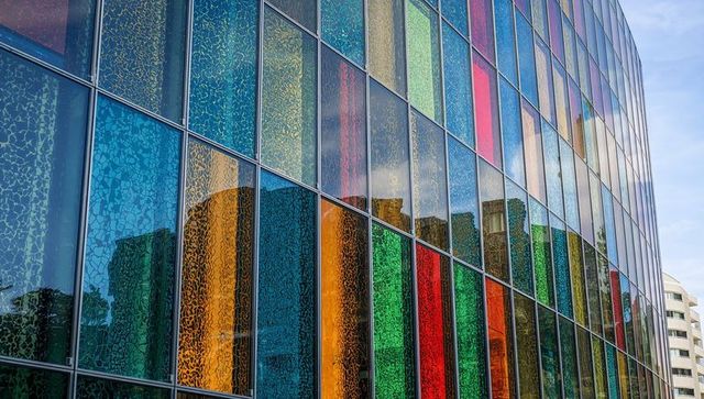 Colorful glass facade of modern skyscraper reflecting urban landscape
