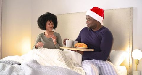 Cozy Christmas Morning Couple Sharing Breakfast in Bed with Santa Hat and Croissant