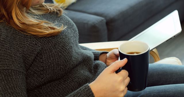 Woman using digital tablet while having coffee at home