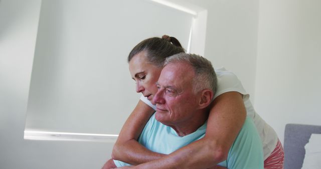 Caucasian senior woman hugging her husband from behind at home. staying at home in self isolation in quarantine lockdown