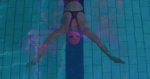 Female Swimmer Gliding Underwater in Pool Lane with Pink Cap