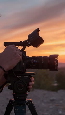 Vertical Sunset Cinematography: Camera Operator Adjusting Viewfinder and Focus