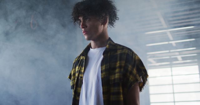 Young Man with Curly Hair in Stylish Plaid Shirt in Smoky Room - Download Free Stock Images Pikwizard.com