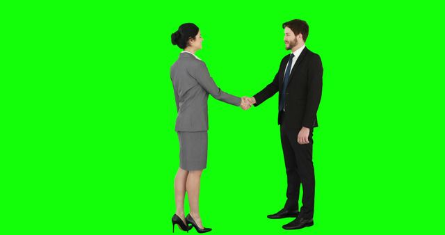 Two businesspeople, a man and a woman, are shaking hands while standing on a green background. Both are dressed in formal attire, with the woman wearing a suit skirt and the man in a suit and tie. This can be used for media related to business agreements, partnerships, professional meetings, teamwork, negotiations, office interactions, and collaborative efforts.