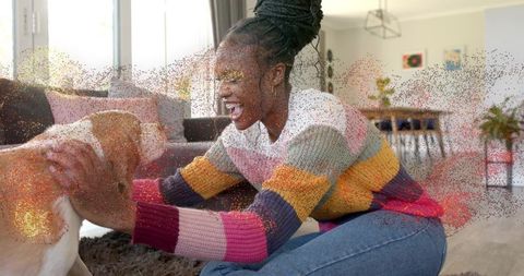 Woman playing with dog on living room rug, wearing colorful knit sweater, sunny cozy