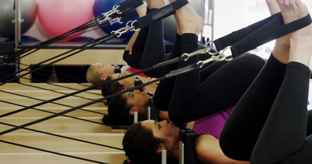 Women engaged in Pilates reformer exercises in a fitness studio, focusing on improving core strength, flexibility, and overall fitness. Suitable for articles or presentations on fitness, Pilates techniques, health benefits of Pilates, or marketing materials for fitness centers and health clubs.