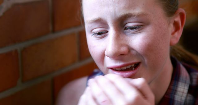 A young Caucasian girl appears to be in distress or experiencing discomfort, with her hands clasped near her face. Her expression and body language suggest she might be upset or in pain, emphasizing the emotional intensity of the moment.