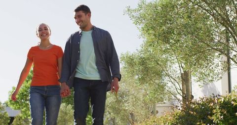 Happy Couple Walking Dog in Sunlit Park Setting