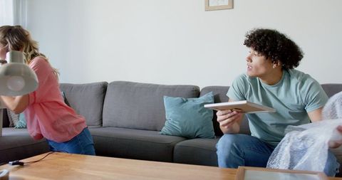 Young couple unwrapping framed picture in cozy living room