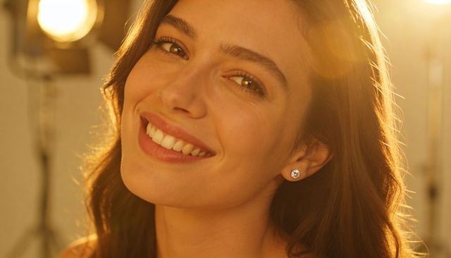 Golden studio portrait of smiling woman tilting head, diamond studs, warm rim light, bokeh