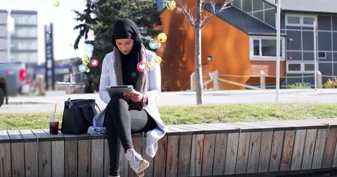 Young Muslim Woman Interacting with Social Media on Tablet