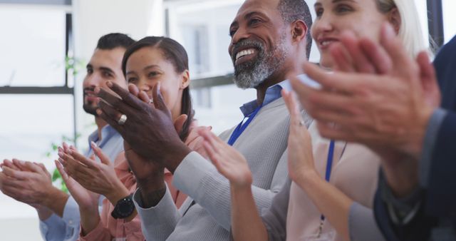 Group of professionals happily applauding together in a corporate environment. Ideal for promoting teamwork, corporate culture, diversity, success, collaboration in business meetings, company events, presentations, and seminars.