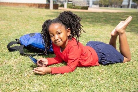 Child relaxing outdoors with smartphone in sunny park