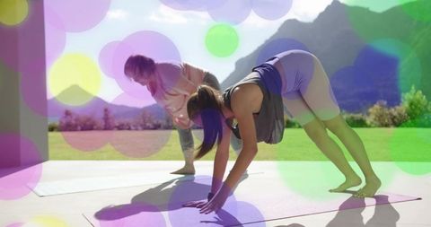 Outdoor yoga coach guiding teen in pike pose on sunlit patio mats with mountain backdrop