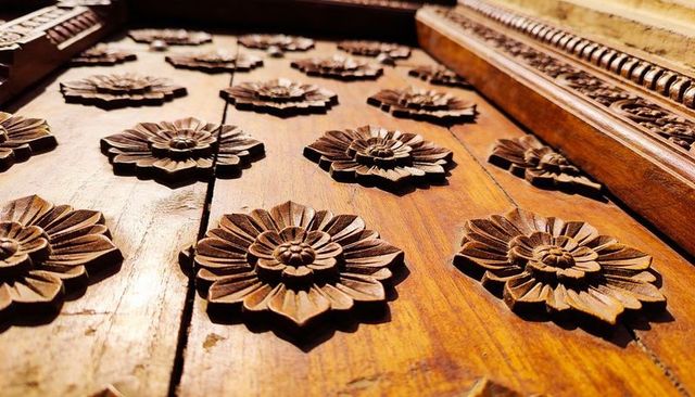 Carved wooden door panel with repeating floral rosettes and warm varnish finish
