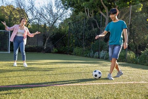 Mother and Son Playing Soccer on Backyard Field