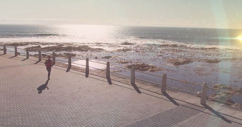 Solo Runner at Sunrise Along Ocean Promenade