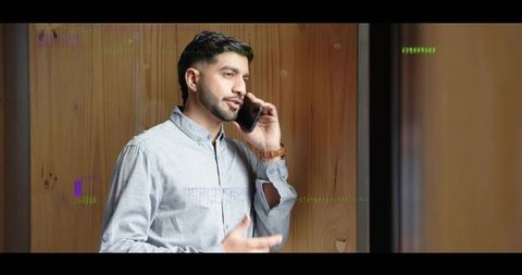 Indian professional engaging in phone conversation in wooden hallway