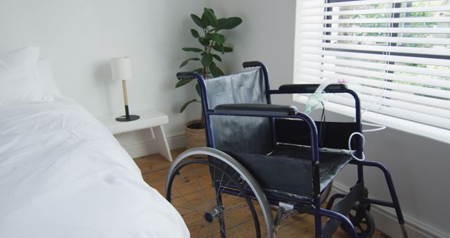 Wheelchair placed next to bed in well-lit modern bedroom with wooden floors and white decor, reflecting accessibility and healthcare support. Suitable for topics on home care, mobility aids, disability support, and home design for accessibility.