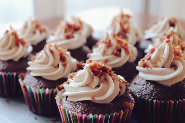 This image showcases a batch of chocolate cupcakes adorned with whipped cream and a crumbled topping. Ideal for use in food blogs, bakery advertisements, recipes, celebration materials, and social media posts emphasizing delicious homemade baked goods.