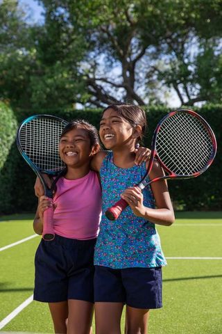 Young Girl Friends Celebrating After Tennis Game Outdoors