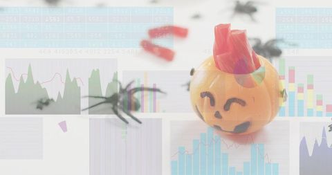 Halloween analytics concept with jack-o'-lantern candy cup, toy spiders and charts overlay