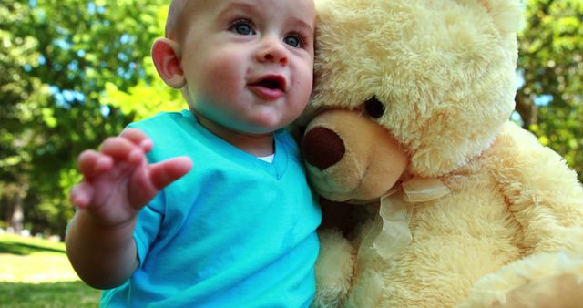 Cute baby boy playing with teddy bear on a sunny day