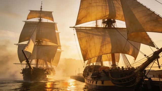Maneuvering twin square-rigged ships into quay at golden sunset, sails glowing
