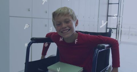 Smiling schoolboy in wheelchair with floating letters in classroom
