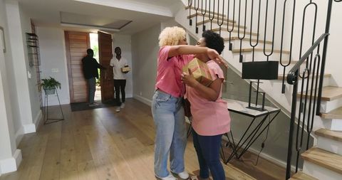 Friends Greeting at Home Entrance with Gifts