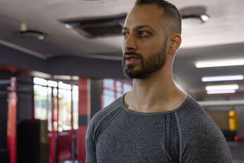 Indian man training in gym wearing fitted grey top boxing and strength workout focused
