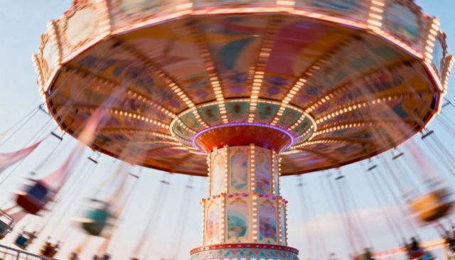 Spinning vintage swing carousel glowing with colorful fairground lights and motion blur