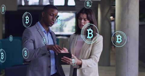 Discussing cryptocurrency on tablet with floating Bitcoin icons, business professionals