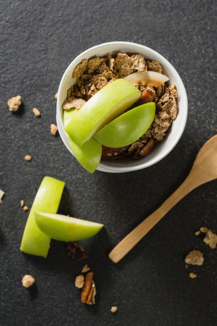 Perfect for promoting healthy eating habits, this image showcases a nutritious breakfast option with granola and fresh green apple slices. Ideal for use in food blogs, nutrition articles, health and wellness websites, or breakfast menu designs.
