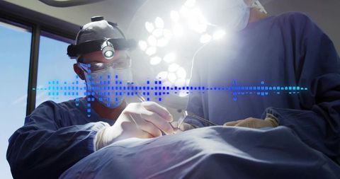 Surgeon performing precision surgery with headlamp and scalpel alongside scrubbed team